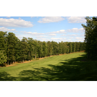 The par-4 16th hole at Timberstone Golf Course features a fairway lined by trees and an elevated green. 